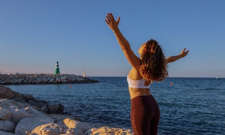 woman in white sports bra and black bottoms standing on seashore