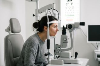 Femme passant un examen de la vue chez l'opticien, regardant dans une lampe à fente en salle d'examen optique