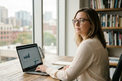 Femme portant des lunettes à monture écaille devant un ordinateur portable dans un bureau moderne
